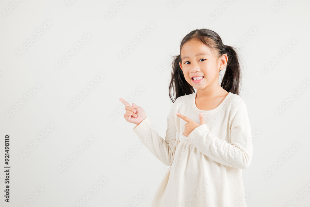 Happy Asian portrait cute young kid girl smiling indicate finger empty space, studio shot isolated on white background, Thai kindergarten child pointing index out with copy space Happy Asian portrait cute young kid girl smiling indicate finger empty space, studio shot isolated on white background, Thai kindergarten child pointing index out with copy space