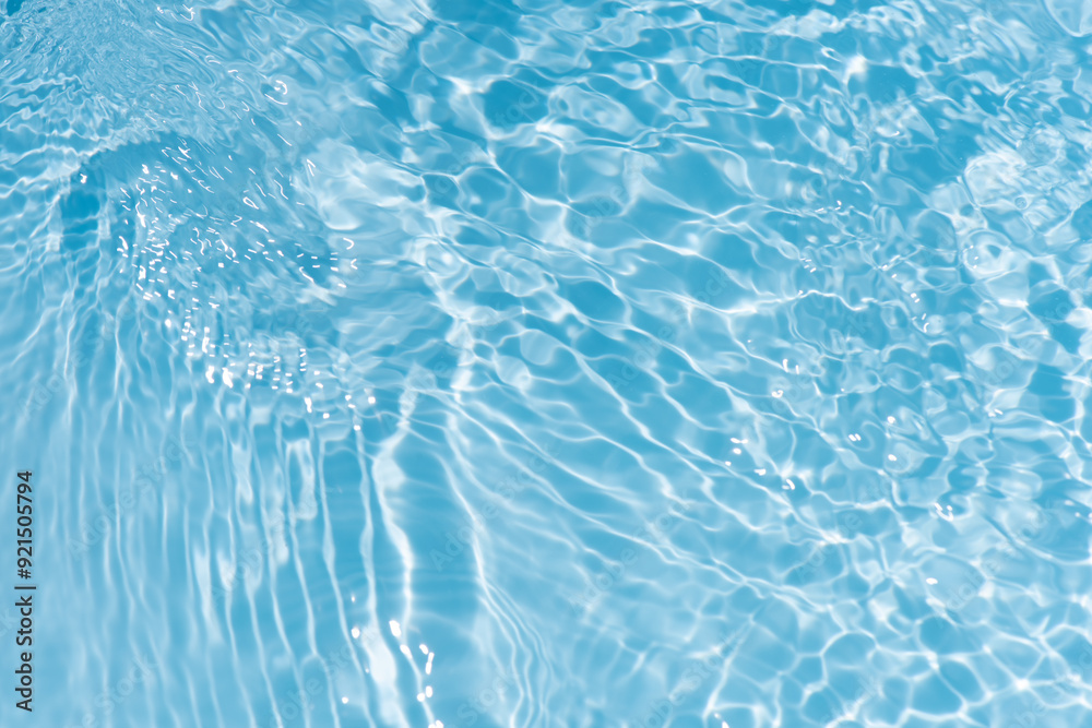 Obraz premium Blue water with ripples on the surface. Defocus blurred transparent blue colored clear calm water surface texture with splashes and bubbles. Water waves with shining pattern texture background.
