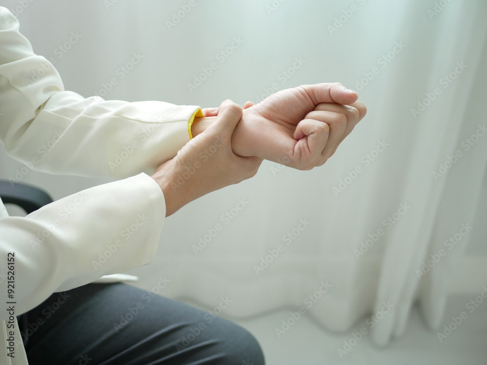 A young businesswoman has severe pain in her wrist. She has numbness. She massages her arm by herself at the office.Health care and office syndrome concept A young businesswoman has severe pain in her wrist. She has numbness. She massages her arm by herself at the office.Health care and office syndrome concept