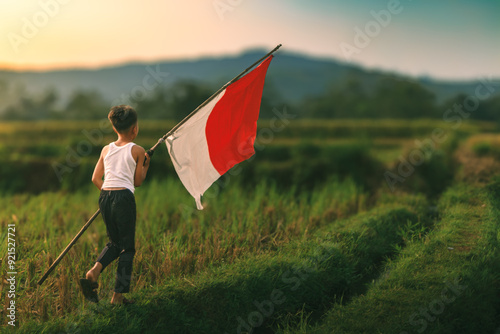A kid holding Indonesian Flag with pole during Indonesian independence day (seorang anak kecil memegang bendera Indonesia dengan tiang waktu hari kemerdekaan Republik Indonesia) photo