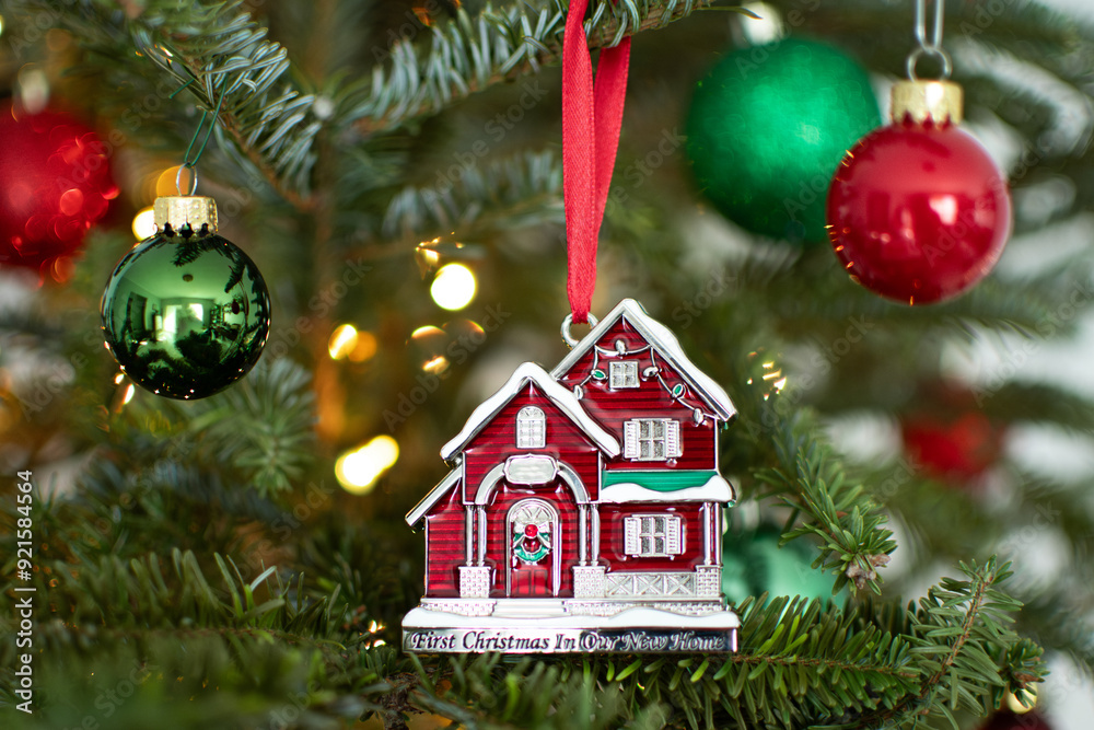 Buying first home concept. House ornament on a Christmas tree. First year in a new house. Buying first real estate. Buying first home concept. House ornament on a Christmas tree. First year in a new house. Buying first real estate.