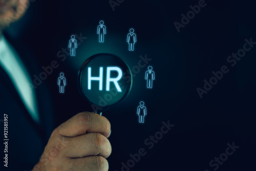 Businessman use the magnifying glass to find human icon for human development recruitment concept. New job, searching for a new team member. Job opportunity hiring concept