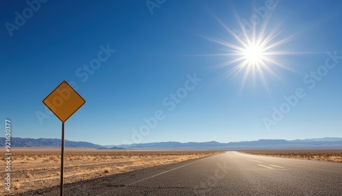 Empty road stretching towards a bright sun in a desert landscape.