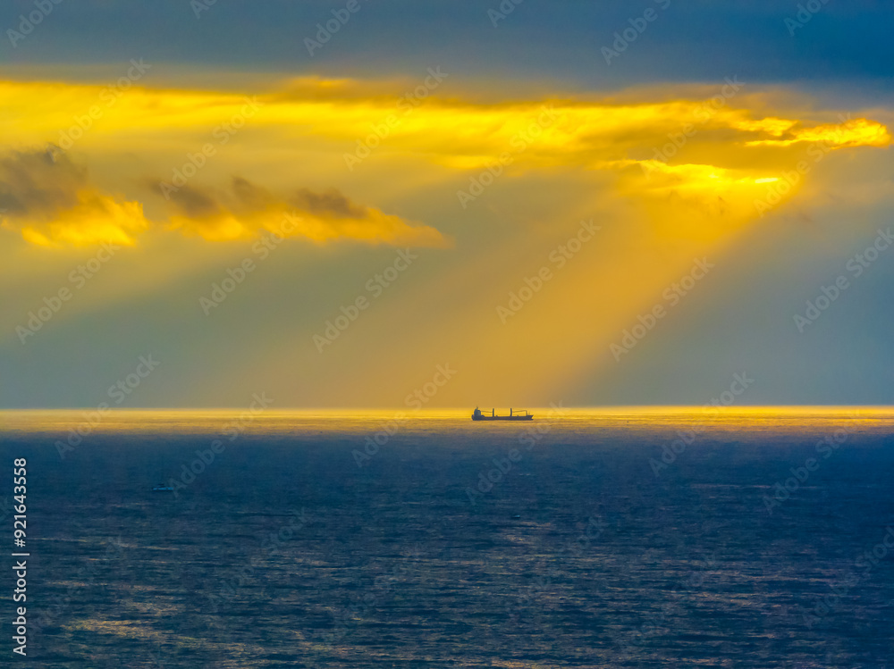 Sunrise Seascape with sunrays in the cloud covered sky and ship on the horizon Sunrise Seascape with sunrays in the cloud covered sky and ship on the horizon