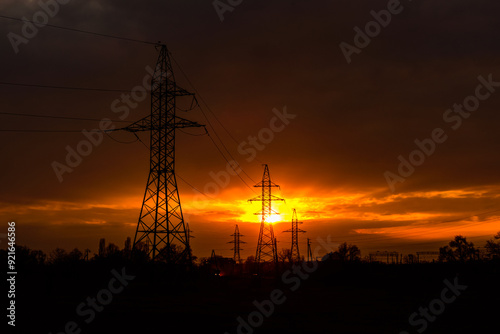 High voltage power line at sunset. Silhouettes of the metal pillars