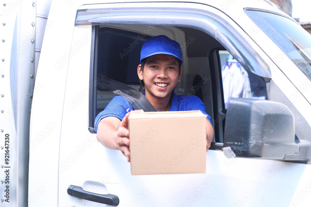 Smiling delivery man sitting in the car as a driver while holding carton package Smiling delivery man sitting in the car as a driver while holding carton package