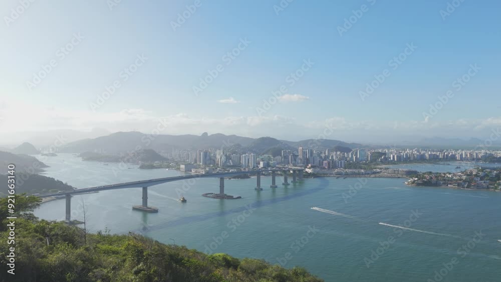 Aerial view of Morro do Moreno revealing the city of Vitória, Espírito Santo, Brazil. Includes roads, commercial buildings, car traffic, blue sky, boats, islands on the horizon, and sunset. Aerial view of Morro do Moreno revealing the city of Vitória, Espírito Santo, Brazil. Includes roads, commercial buildings, car traffic, blue sky, boats, islands on the horizon, and sunset.