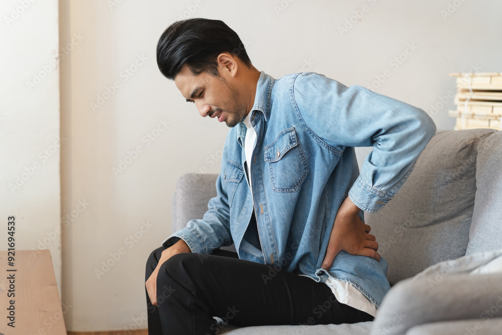 Men sitting on the sofa and suffering pain at his lower back. Men sitting on the sofa and suffering pain at his lower back.