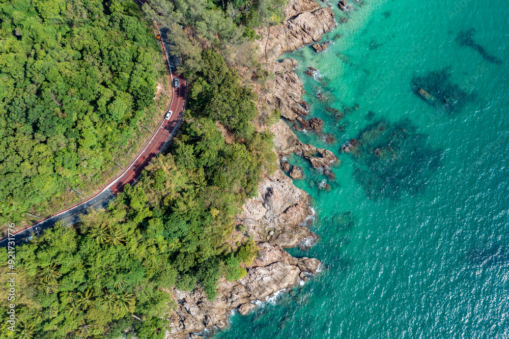 Obraz premium Aerial view of two cars on the road running along the rocky coastline