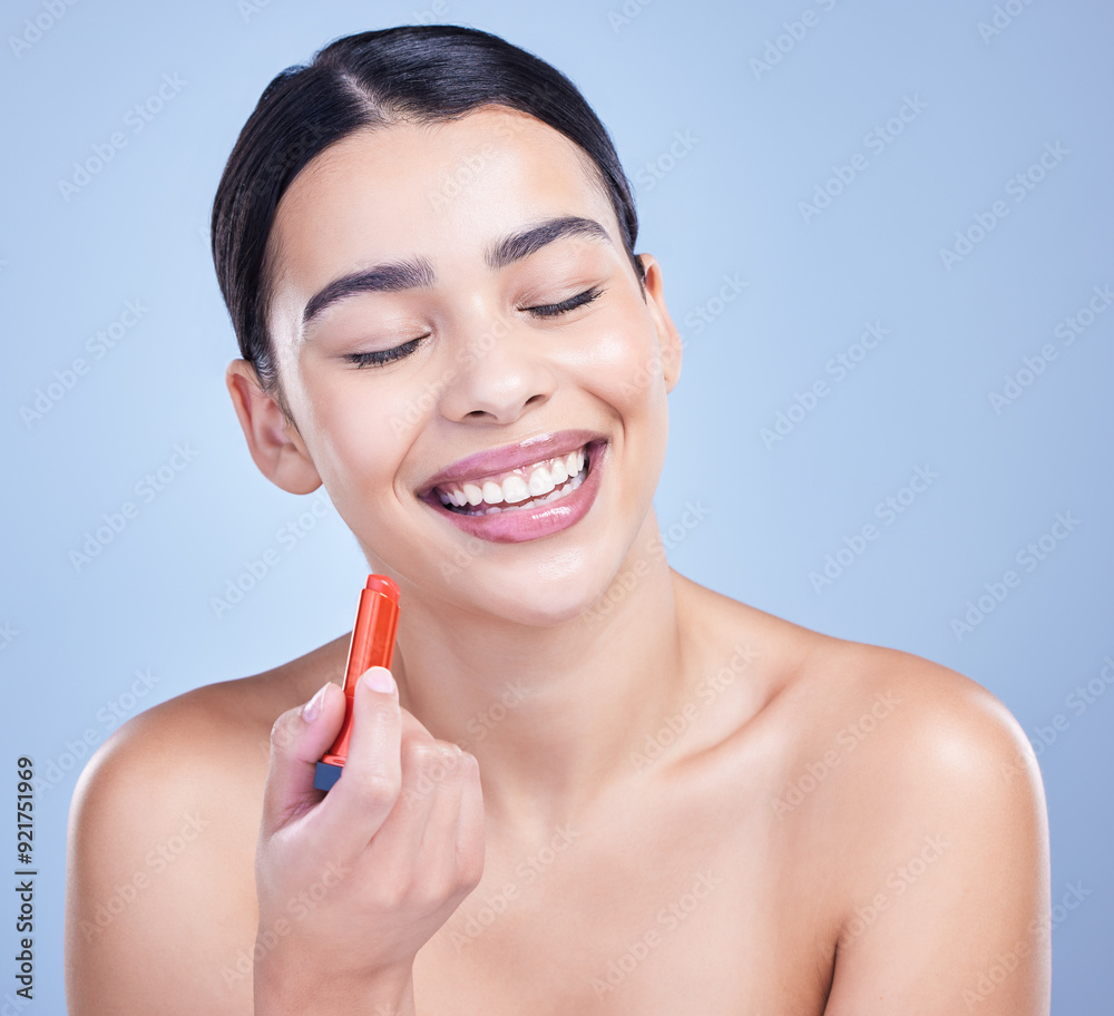 Woman, laughing and red lipstick in studio with makeup for beauty cosmetics on blue background. Smile, funny person or model applying color, gloss or glow for cosmetology, dermatology or treatment Woman, laughing and red lipstick in studio with makeup for beauty cosmetics on blue background. Smile, funny person or model applying color, gloss or glow for cosmetology, dermatology or treatment