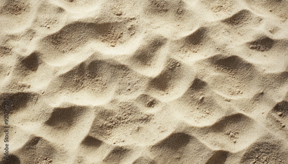 Textured sandy surface with gentle waves under bright sunlight in a coastal area Textured sandy surface with gentle waves under bright sunlight in a coastal area