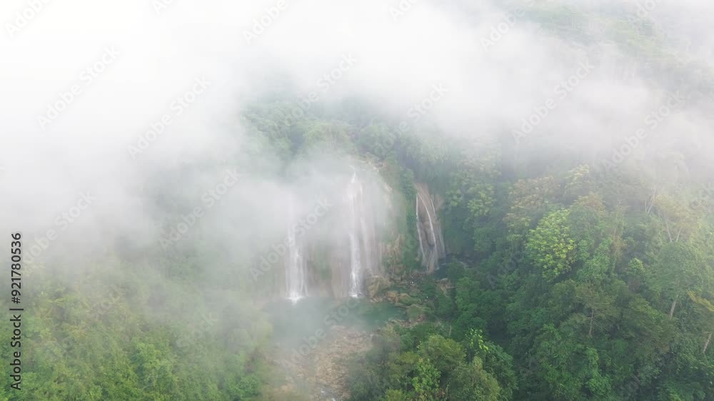 A majestic waterfall in the rainforest shrouded in mist in the morning A majestic waterfall in the rainforest shrouded in mist in the morning