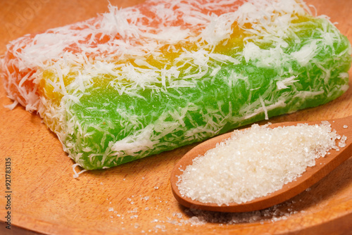 Sentiling, or Lapis Singkong, is a sweet Indonesian snack made from cassava, colored red, yellow, and green. Served with grated coconut or sugar. Photographed on a white background. photo