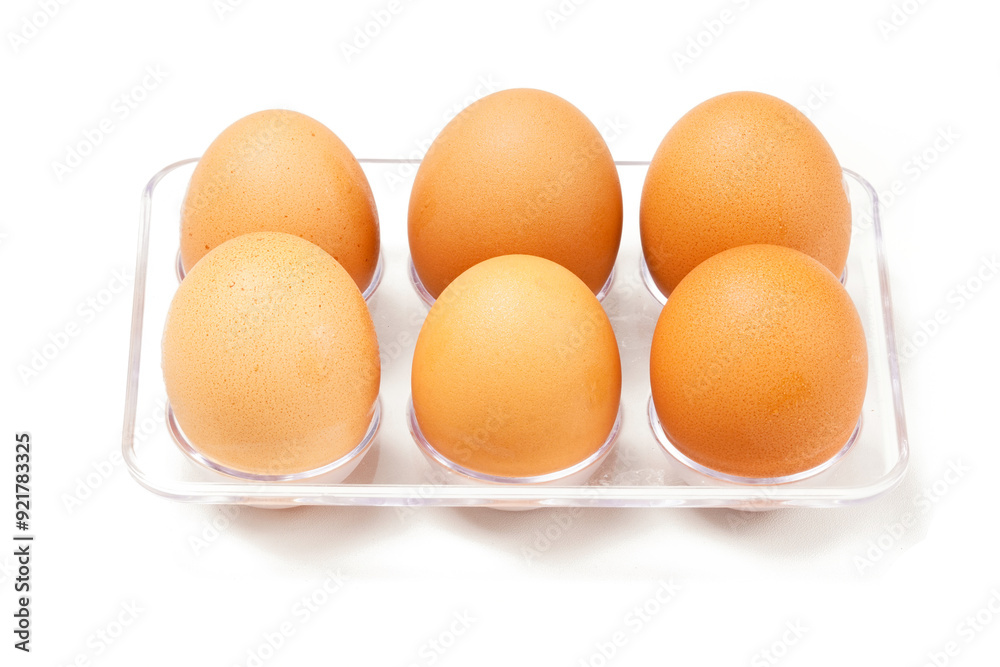 A row of light brown chicken eggs placed in a transparent holder, typically stored in the fridge. Photographed against a white background. A row of light brown chicken eggs placed in a transparent holder, typically stored in the fridge. Photographed against a white background.