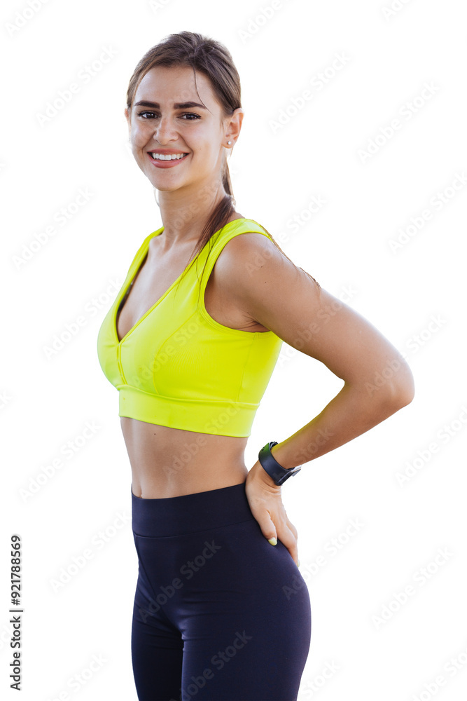 Attractive young Spanish woman standing against transparent background in sport bra and pants looking at camera smiling satisfied by her body shape and health. 