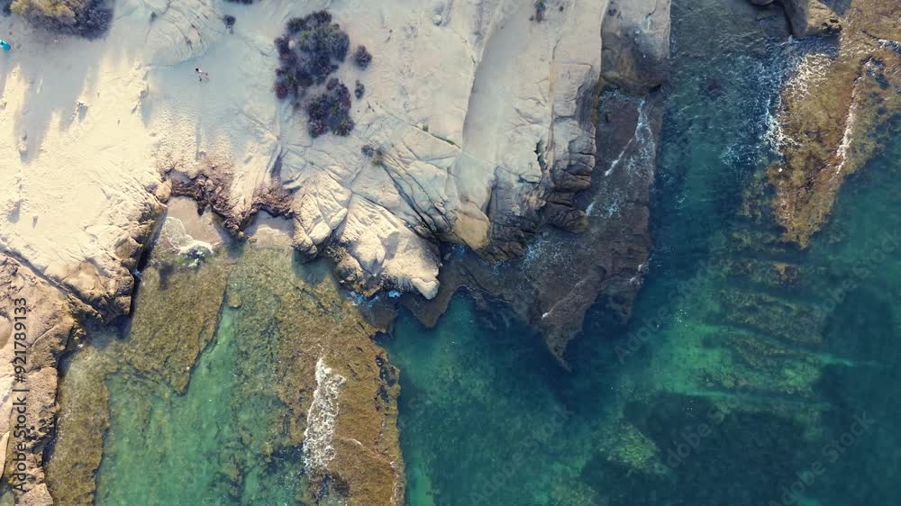 Aerial view of a rocky shoreline next to a calm water body Aerial view of a rocky shoreline next to a calm water body