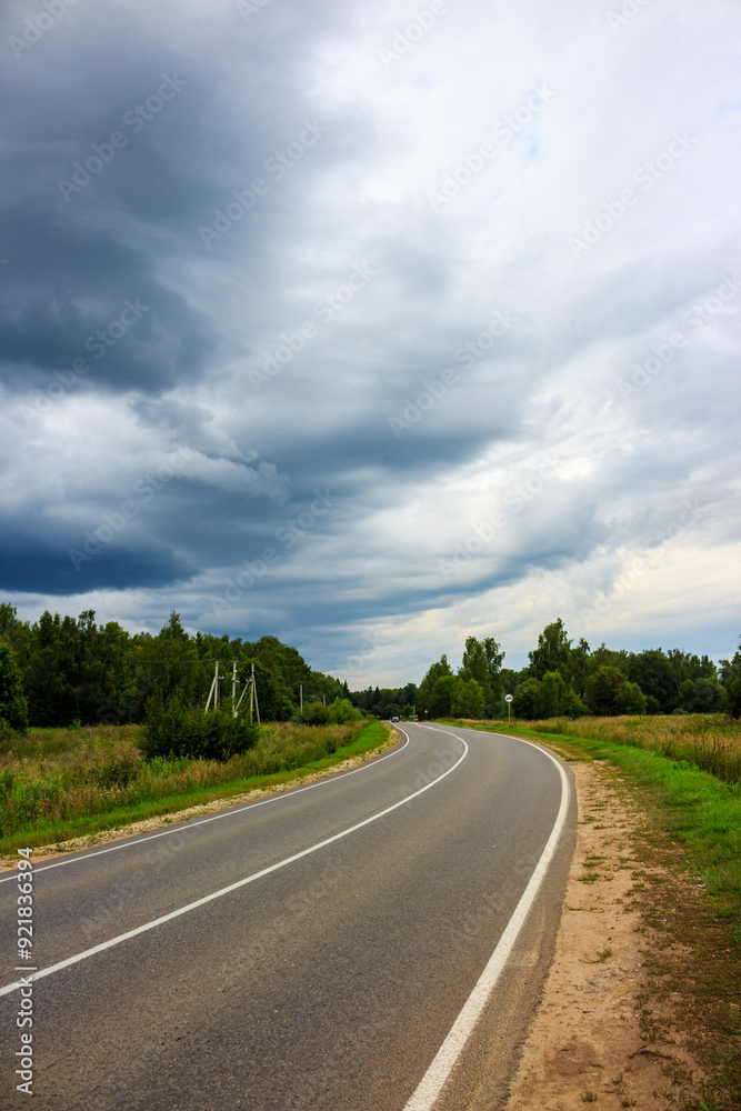 Menacing rain clouds moving towards the highway, landscape before the downpour Menacing rain clouds moving towards the highway, landscape before the downpour