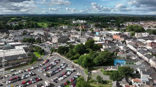 Monaghan Town, County Monaghan, Ireland, September 2022. Drone pushes towards Church Square above parks with trees lining car parks around St. Patrick Church with apartments in old town center. photo