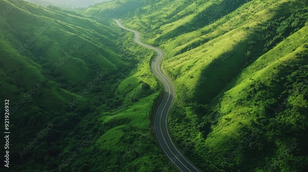 Aerial perspective of a scenic road winding through a mountain pass with lush greenery. Perfect for outdoor and adventure content