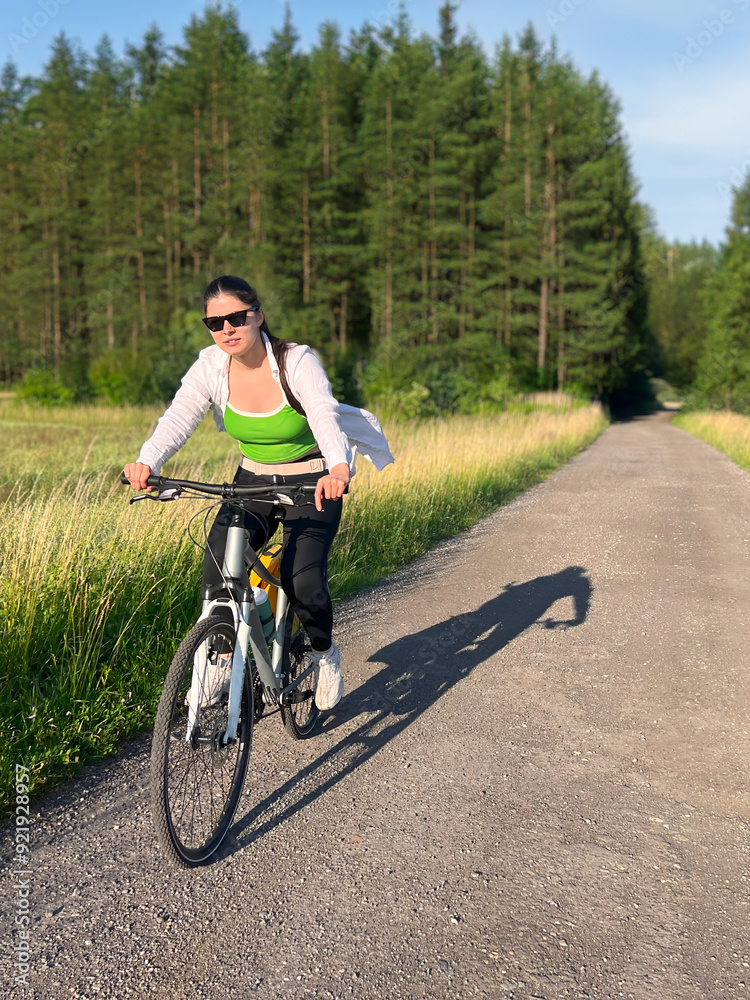 Obraz premium Woman riding bicycle along peaceful countryside road
