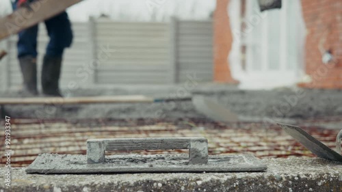 Worker leveling concrete on a construction site during winter