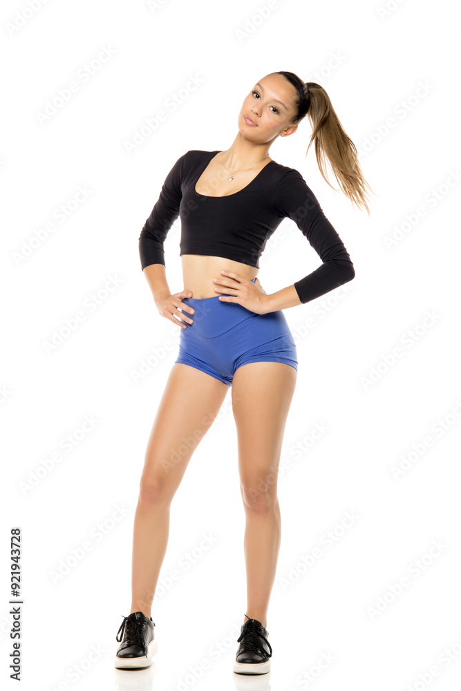 Sporty fit woman in blue shorts and black shirt isolated on white studio background. Full body of slim attractive female with flat belly Sporty fit woman in blue shorts and black shirt isolated on white studio background. Full body of slim attractive female with flat belly