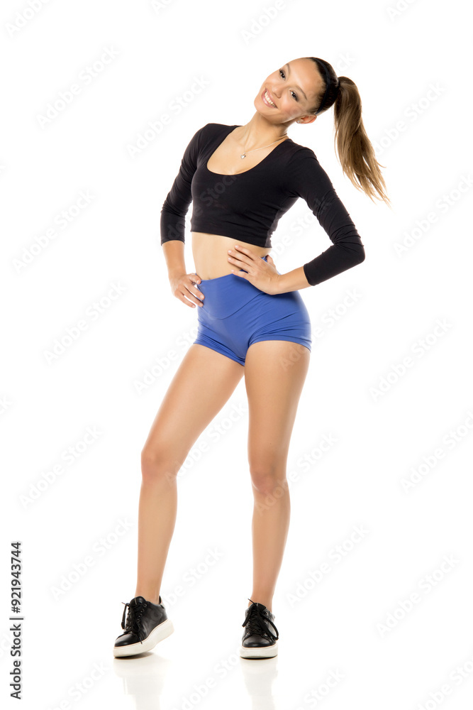 Sporty fit smiling woman in blue shorts and black shirt isolated on white studio background. Full body of slim attractive female with flat belly Sporty fit smiling woman in blue shorts and black shirt isolated on white studio background. Full body of slim attractive female with flat belly