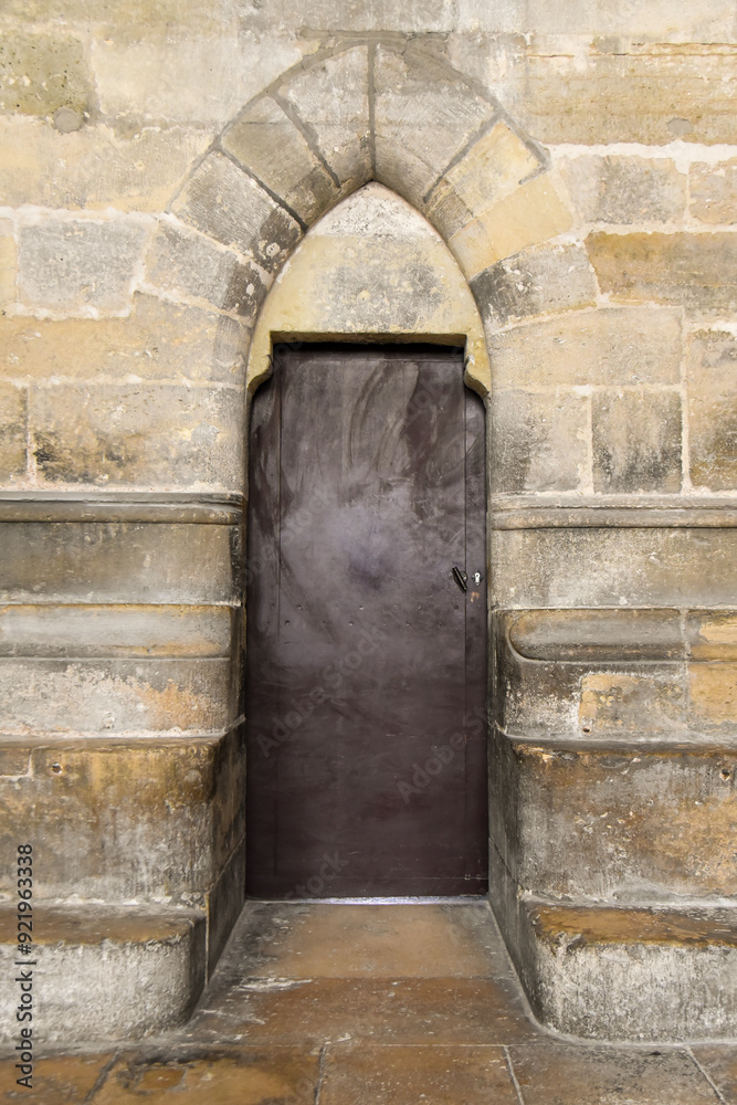 old door under a narrow arch in the cathedral of Reims