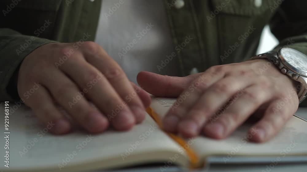 Close-up of a man's hands turning the pages of a book. A man is reading a book. Close-up of a man's hands turning the pages of a book. A man is reading a book.