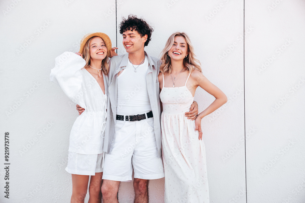 Young three stylish friends posing in the street. Fashion man and two cute female dressed in casual summer clothes. Smiling models having fun. Cheerful women and guy outdoors, in sunny day, sunglasses Young three stylish friends posing in the street. Fashion man and two cute female dressed in casual summer clothes. Smiling models having fun. Cheerful women and guy outdoors, in sunny day, sunglasses
