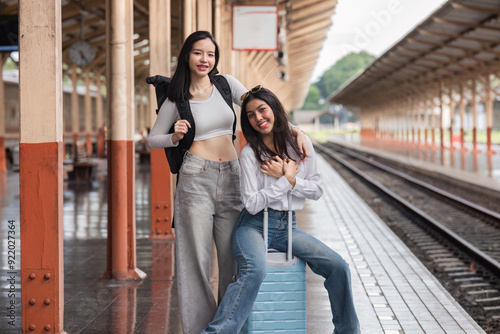 Young Female Friends Waiting for the Train Together at the Station with Luggage and Backpacks