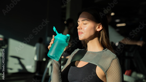 fitness woman in sport wear with perfect sexy fitness body in gym drinking from shaker bottle after training