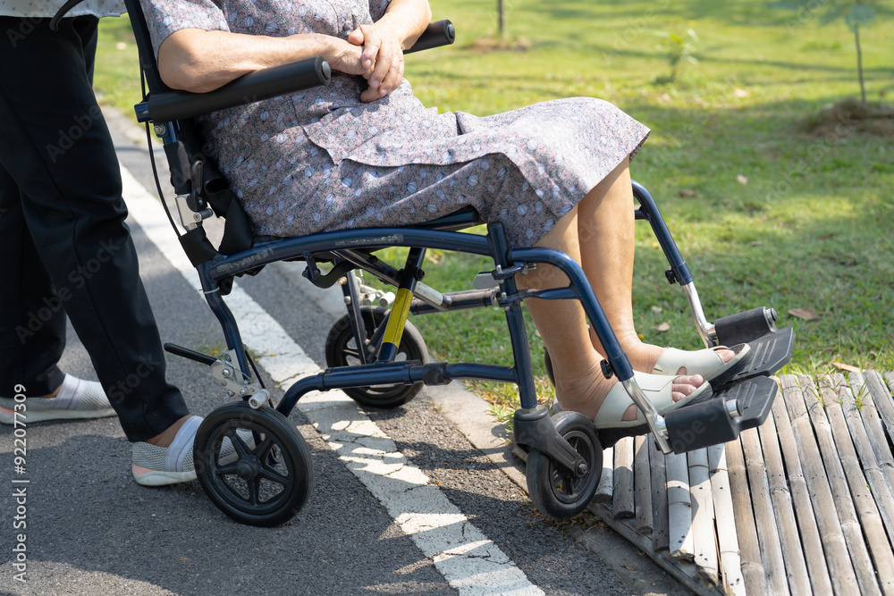 Obraz premium Caregiver help and care Asian senior woman patient sitting on wheelchair to ramp in nursing hospital, healthy strong medical concept.