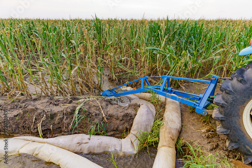 Agricultural machinery parked beside a farmland for drainage in the summer evening