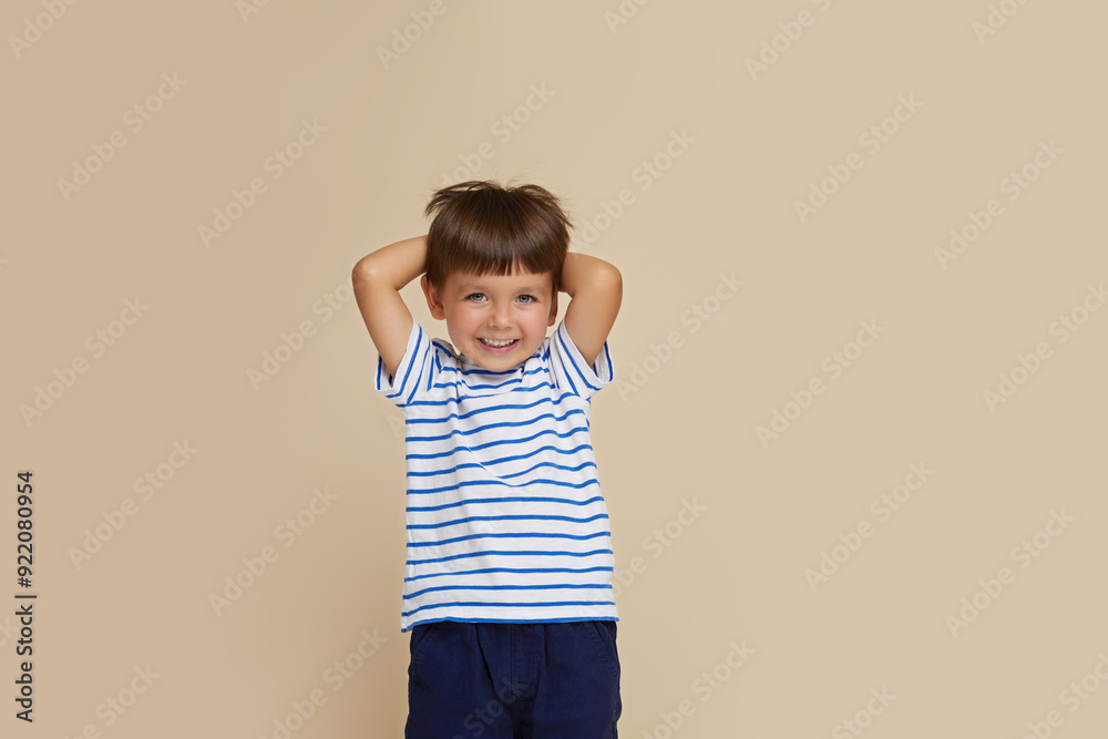 Front portrait of a little boy being very happy, isolated over beige background. Copy space. Front portrait of a little boy being very happy, isolated over beige background. Copy space.