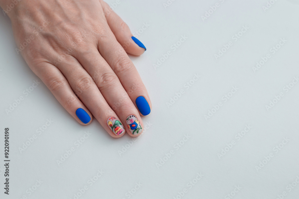 Beauty service. Female hand with blue manicured nails and flowers design. Gel varnish nail art. White background, copy space. Beauty service. Female hand with blue manicured nails and flowers design. Gel varnish nail art. White background, copy space.