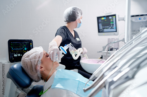 Doctor making anesthesia while female patient lying in dentist chair photo