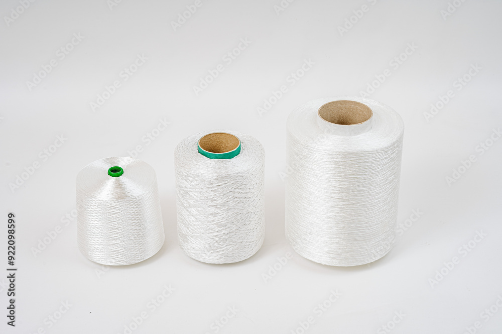 Three spools of white fiberglass yarn in different sizes are aligned in a row against a plain white background, showcasing their texture and form. Three spools of white fiberglass yarn in different sizes are aligned in a row against a plain white background, showcasing their texture and form.