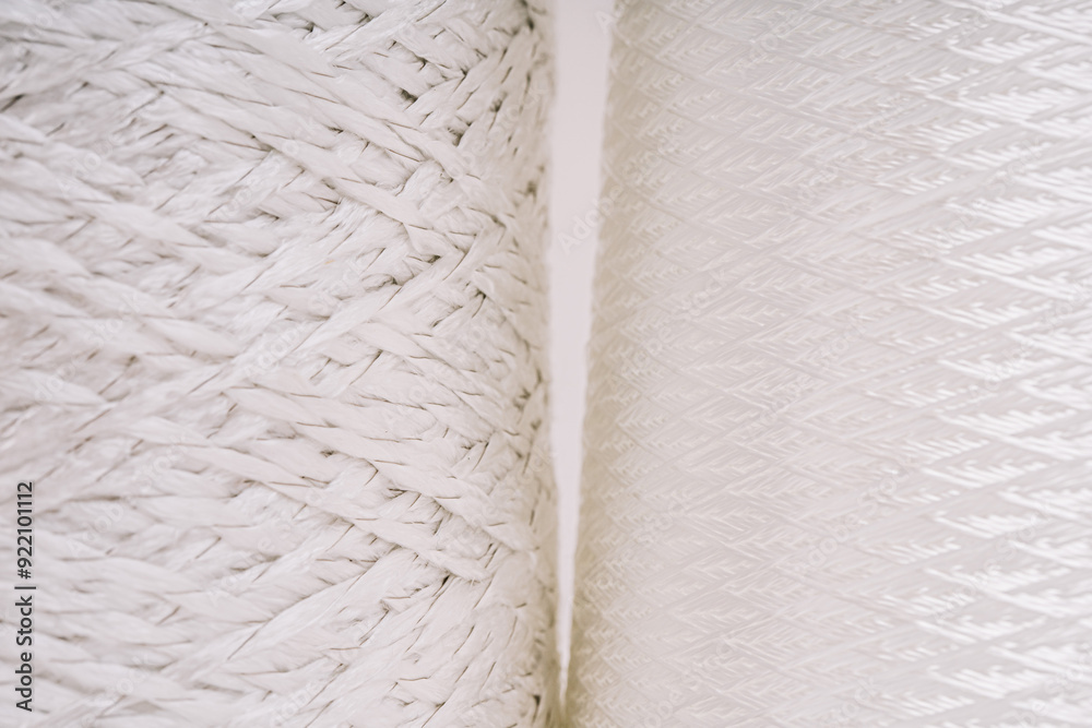 Obraz premium Close-up of two spools of white fiberglass thread, highlighting the intricate woven and braided textures of the material.
