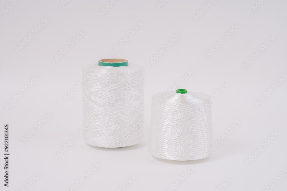  Two spools of white fiberglass thread, one taller with a green core and the other shorter with a green tip, placed on a white background.