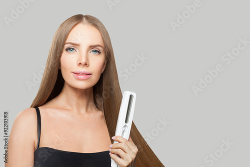 Fashionable woman with long hair using a straight hair iron and doing a hairstyle, beauty, care and fashion concept