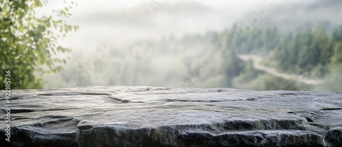 Rough stone tabletop with sharp, rugged textures, set against a blurred misty valley, detailed natural surface, rustic tabletop photo