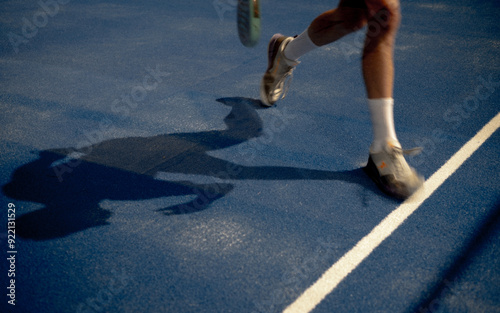 Person playing padle on a blue court on a summer sunny day