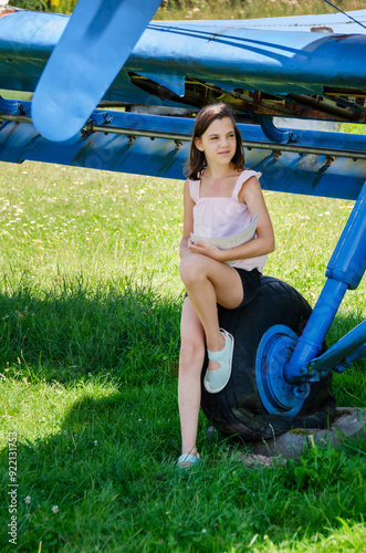 Preteen girl sitting near small helicopter at airfield photo