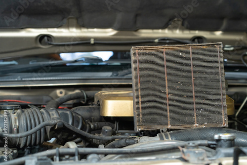 Old air filter on the hood of a car. Close-up.The old car air filter has expired and must be replaced.