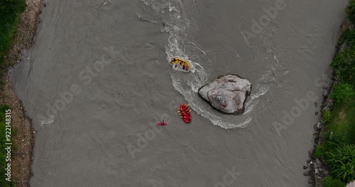 Drone shot tourists rafting flooded Bhotekoshi River monsoon in Nepal, adventurous and life-risking experience navigating around huge rock and dealing powerful currents, thrilling dangerous tourism photo