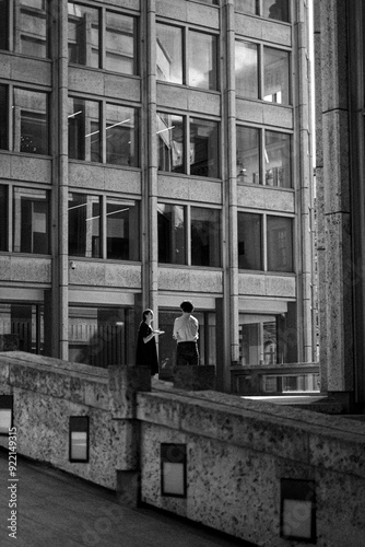 Man and woman talking, standing in the distance among buildings on a summer day in London
