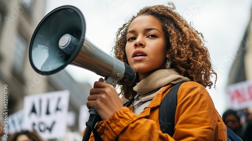 A candid portrait of a young activist passionately speaking into a megaphone during a peaceful protest, surrounded by signs advocating for equality and justice