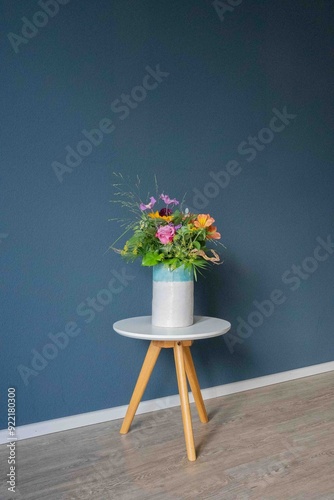 Blumenstrauß auf weißem Tisch mit blauer Wand photo