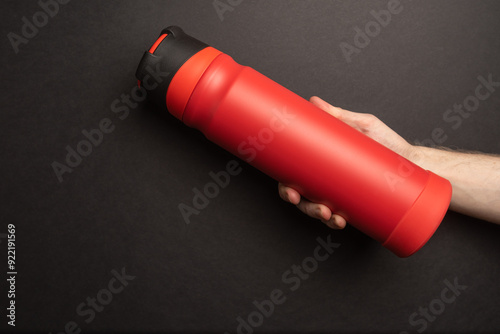 red thermos in the hands of man